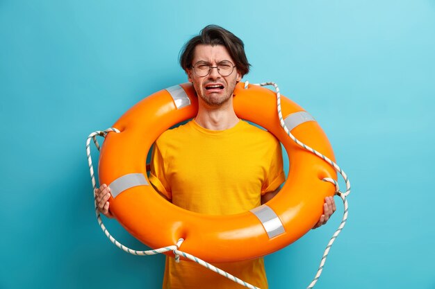 Hombre caucásico infeliz aprende a nadar poses con salvavidas se prepara para viaje en crucero