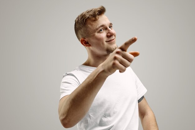 Hombre caucásico joven hermoso elegante que señala en el estudio. Concepto de emociones humanas