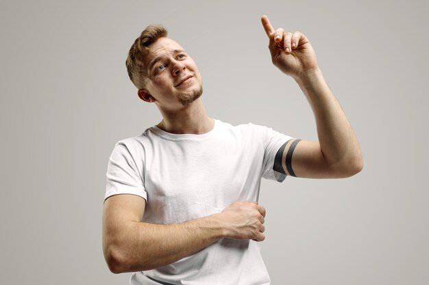 Hombre caucásico joven hermoso elegante que señala en el estudio. Concepto de emociones humanas