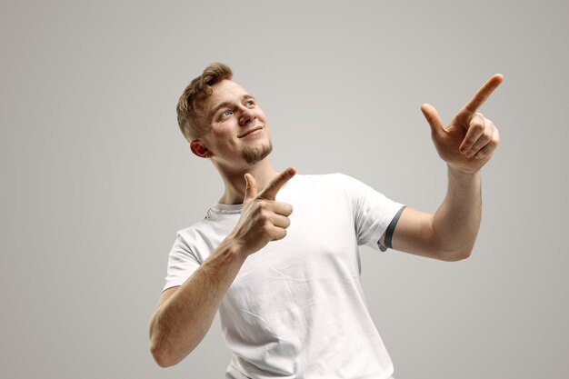 Hombre caucásico joven hermoso elegante que señala en el estudio. Concepto de emociones humanas