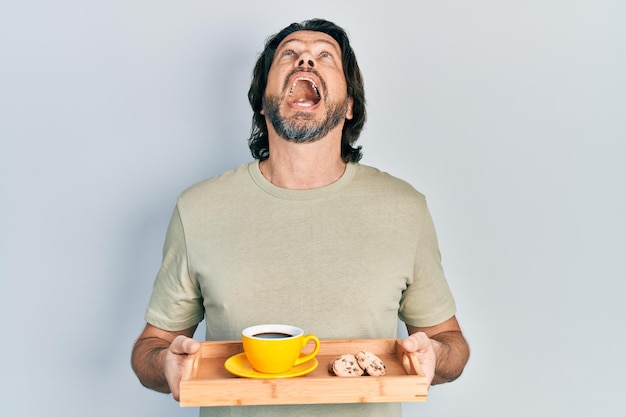 Foto gratuita hombre caucásico de mediana edad sosteniendo una bandeja de desayuno con galletas y café enojado y enojado gritando frustrado y furioso gritando con ira mirando hacia arriba