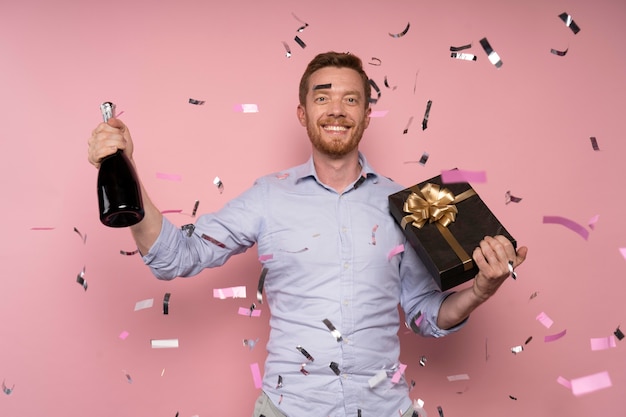 Hombre celebrando con botella de champán y presente