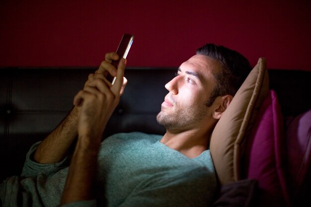 Hombre centrado usando Smartphone en el sofá en la noche