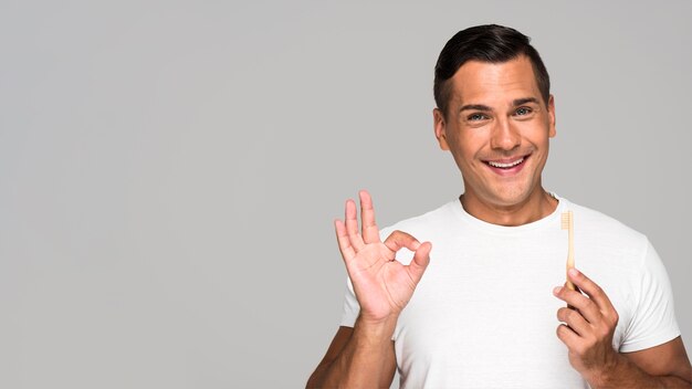 Hombre con cepillo de dientes mostrando aprobación