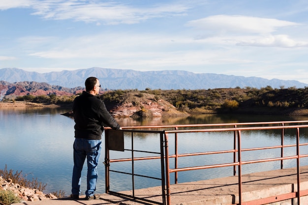 Hombre cerca del lago disfrutando de la luz del sol