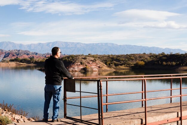 Hombre cerca del lago disfrutando de la luz del sol