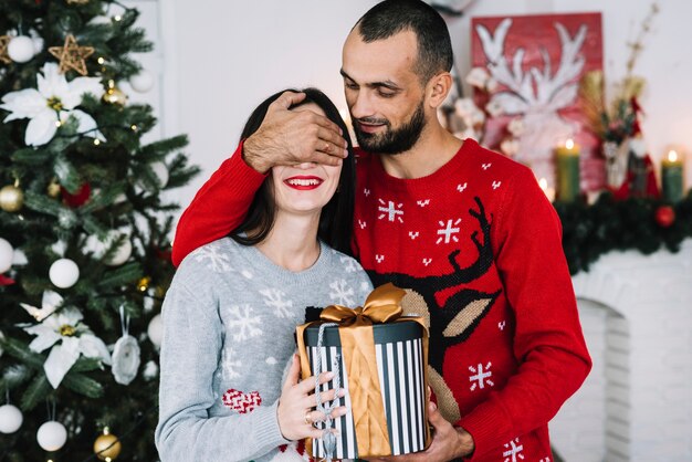 Hombre cerrando los ojos a la mujer con regalo