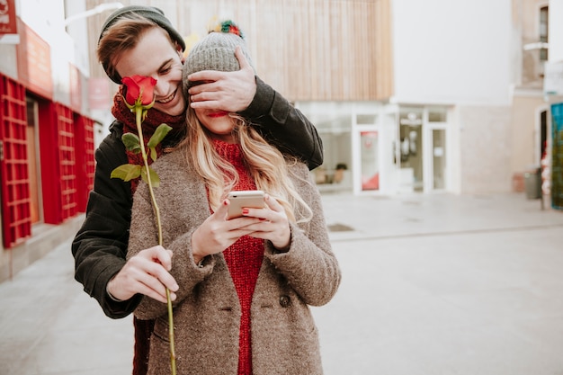 Foto gratuita hombre cerrando los ojos a la novia y dando rosa