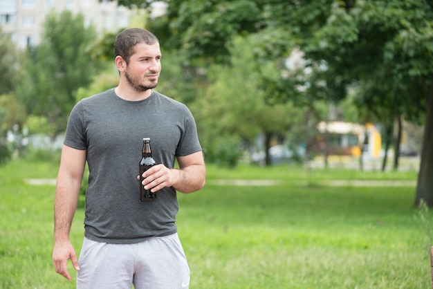 Hombre con cerveza mirando a otro lado en el parque