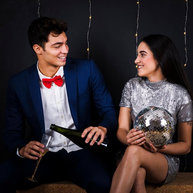 Hombre con champagne y mujer con bola de discoteca