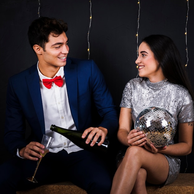 Hombre con champagne y mujer con bola de discoteca