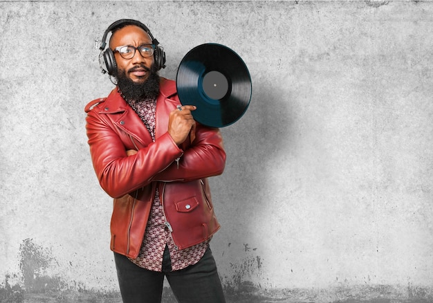 Hombre con chaqueta de cuero escuchando música y sujetando un disco de vinilo