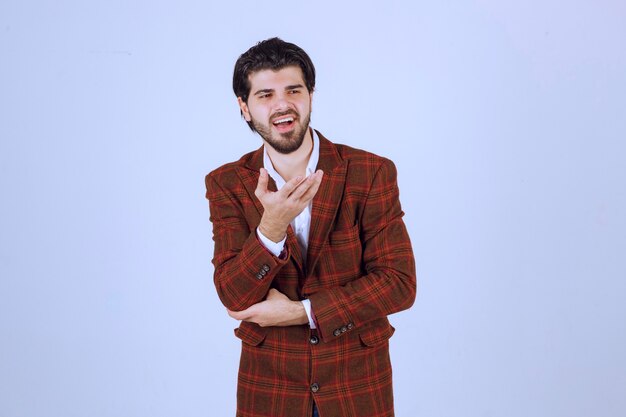 Hombre de chaqueta marrón apuntando e introduciendo algo a la derecha.