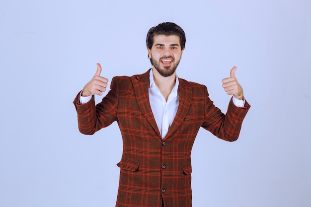 Hombre de chaqueta marrón haciendo pulgar arriba signo.