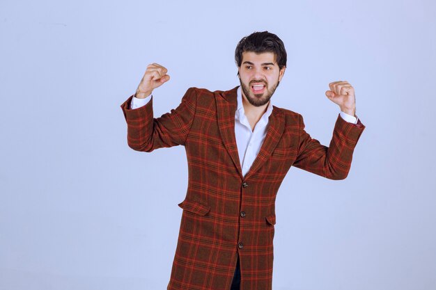 El hombre con chaqueta marrón muestra sus puños y siente una gran motivación.