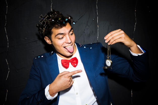 Foto gratuita hombre en chaqueta de noche mostrando la lengua y el reloj de bolsillo