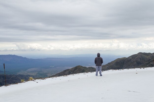 Hombre con una chaqueta de pie en la cima de una montaña en la Reserva Natural de Villavicencio en Mendoza, Argentina.