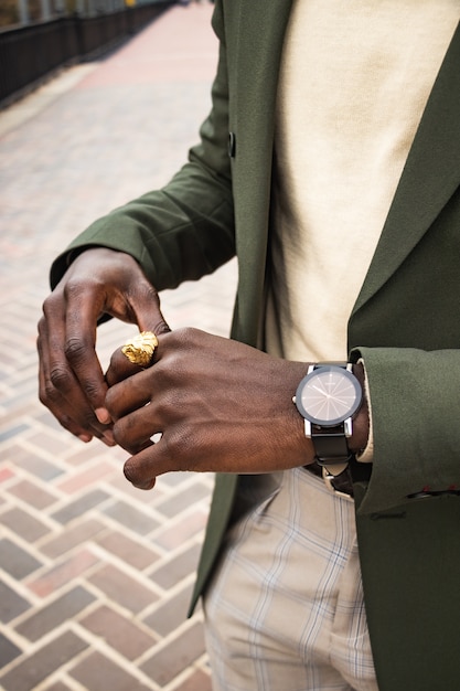 Hombre de chaqueta verde con reloj y anillo de león de color dorado