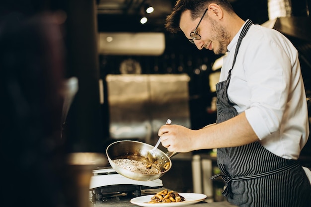 Hombre chef cocinando pollo asiático en la cocina de un café