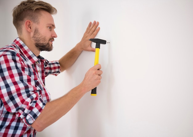 Hombre clavando un clavo en la pared