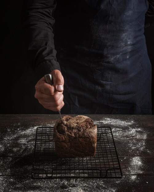 Foto gratuita hombre clavando un cuchillo en el pan vista alta