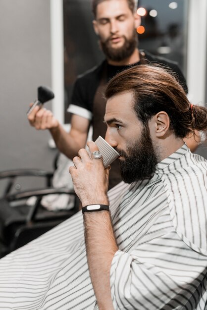 Hombre cliente bebiendo una taza de té en peluquería