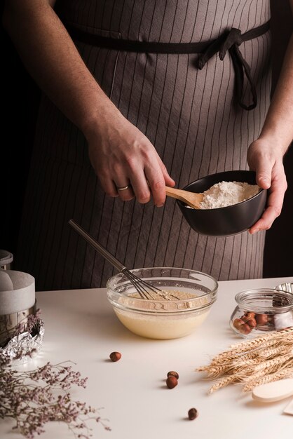 Hombre cocinero agregando harina en un tazón de mezcla