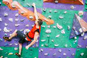 Foto gratuita hombre colgado en la pared de escalada