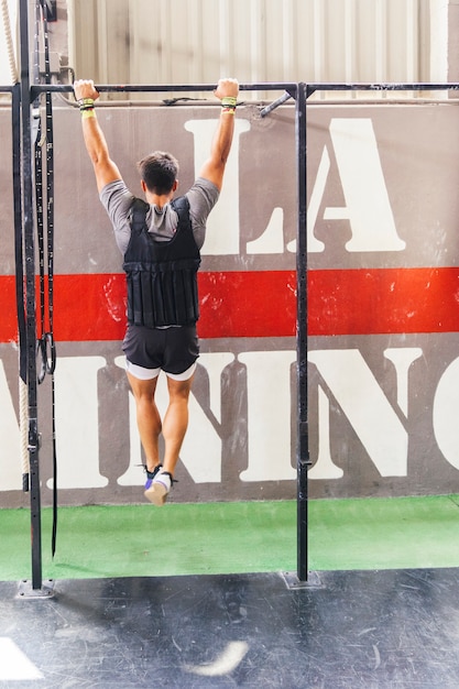 Foto gratuita hombre colgando en barra en gimnasio