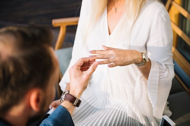 Hombre colocando el anillo de compromiso en el dedo de la novia