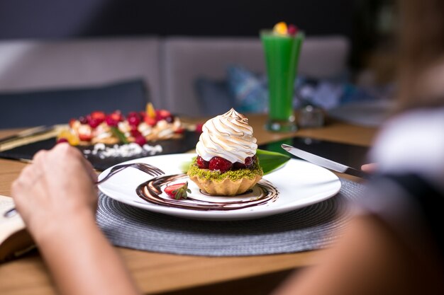 El hombre va a comer tartaletas con pistachos, crema de fresa, chocolate, vista lateral