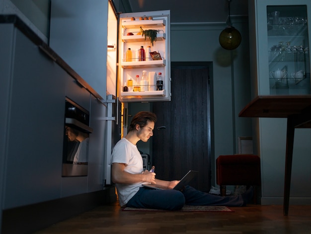 Foto gratuita hombre comiendo bocadillos por la noche tiro completo