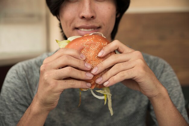 Hombre comiendo hamburguesa en café