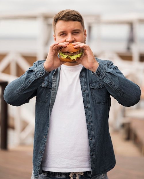 Foto gratuita hombre comiendo hamburguesa de tiro medio