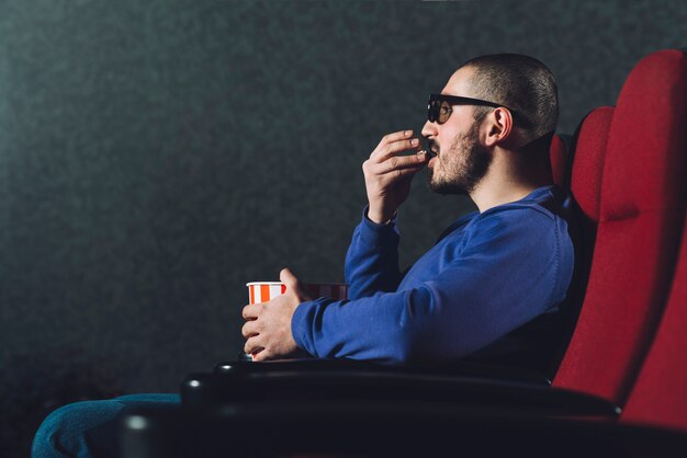 Hombre comiendo palomitas de maíz en el cine