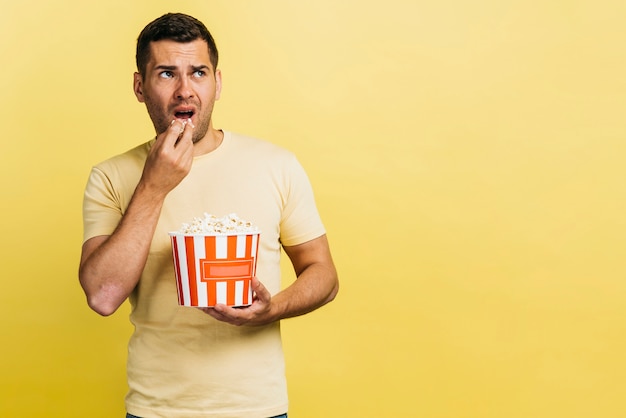 Foto gratuita hombre comiendo palomitas de maíz con espacio de copia