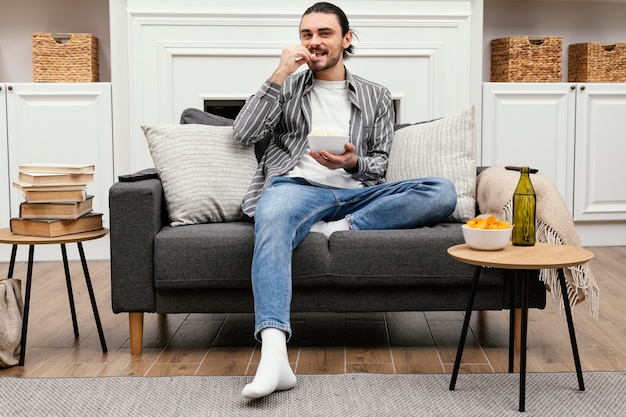 Hombre comiendo palomitas de maíz y viendo la televisión tiro largo