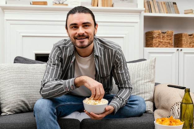 Hombre comiendo palomitas de maíz y viendo la televisión vista frontal