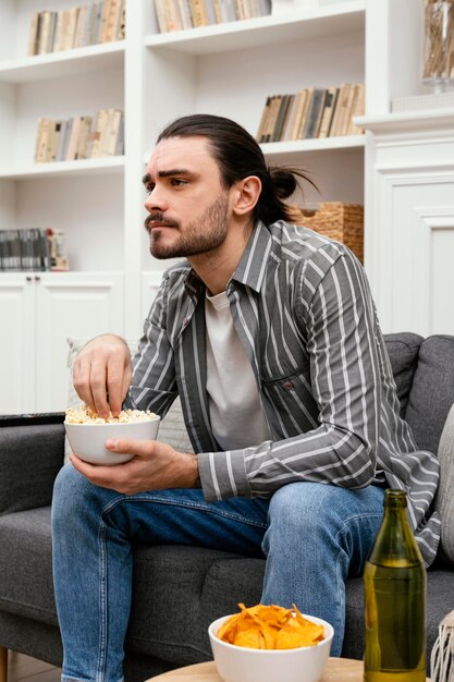 Hombre comiendo palomitas de maíz y viendo la televisión vista lateral