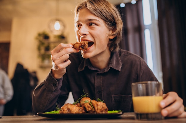 Hombre comiendo pollo frito con salsa en un café