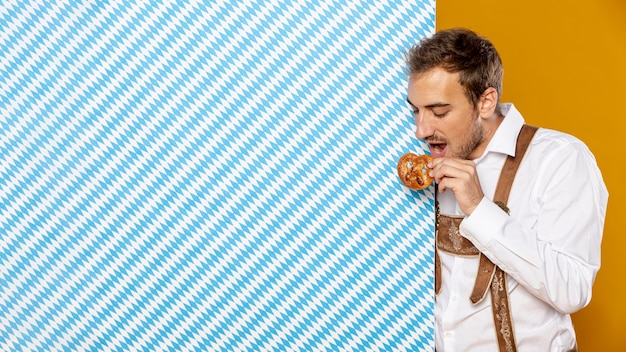 Foto gratuita hombre comiendo pretzel con espacio de copia