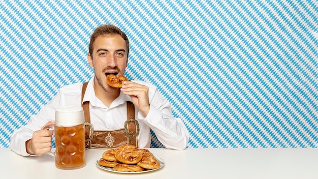 Foto gratuita hombre comiendo pretzels alemanes con espacio de copia