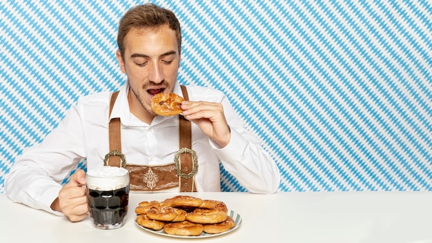 Hombre comiendo pretzels con cerveza negra