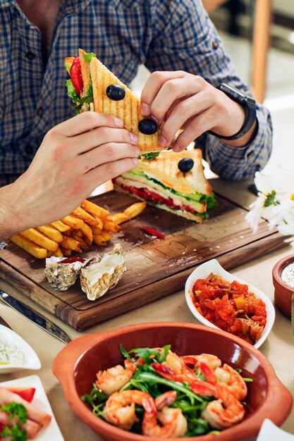 Hombre comiendo sándwich club en un restaurante.