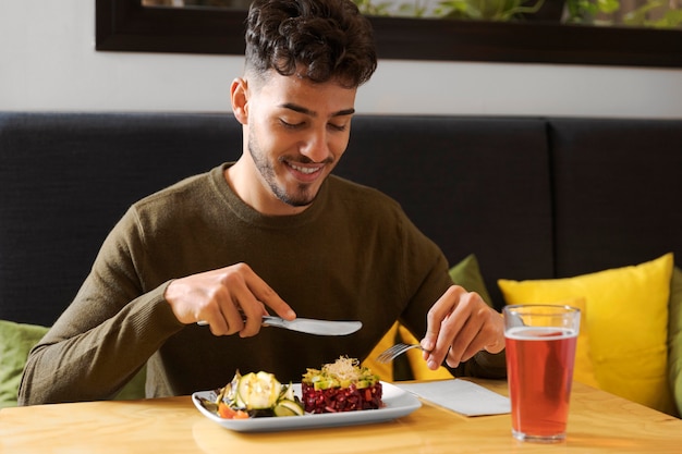 Hombre comiendo sonriente de tiro medio