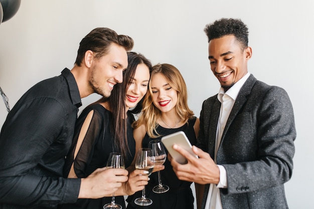 Hombre complacido en chaqueta de tweed vintage haciendo selfie con amigos en la fiesta de cumpleaños