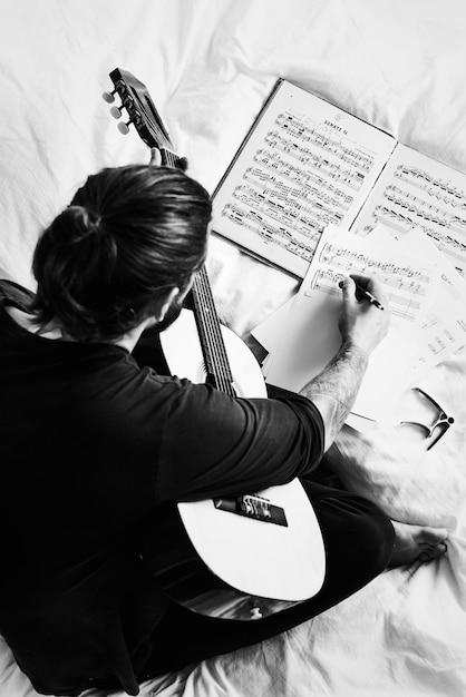 Hombre componiendo una canción en una guitarra