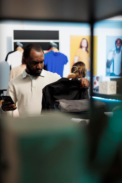 Foto gratuita hombre comprando camisa y comprobando la aplicación