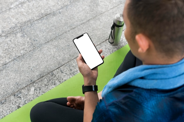 Hombre comprobando el teléfono inteligente antes de hacer algo de yoga