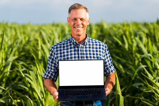 Hombre con una computadora portátil en una maqueta de maizal